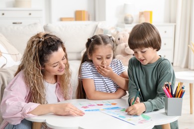 Photo of Mother and her children drawing at white table indoors