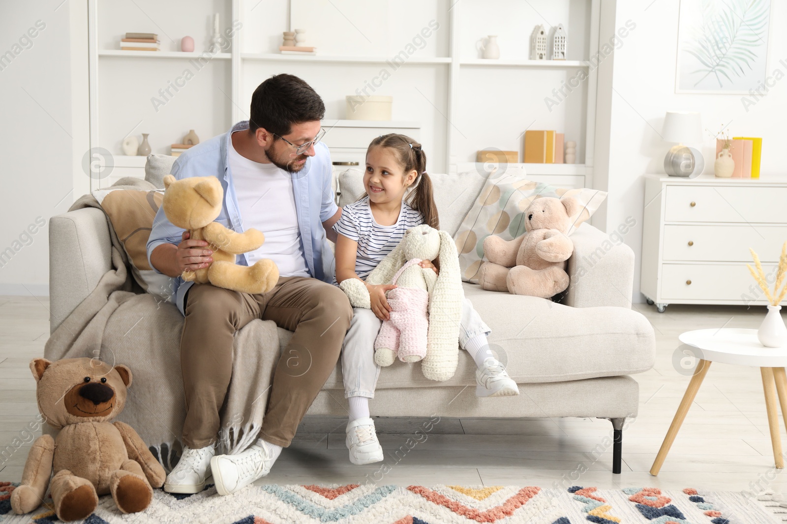 Father and his daughter playing with stuffed animals on sofa at home Photo of Father and his daughter playing with stuffed animals on sofa at home