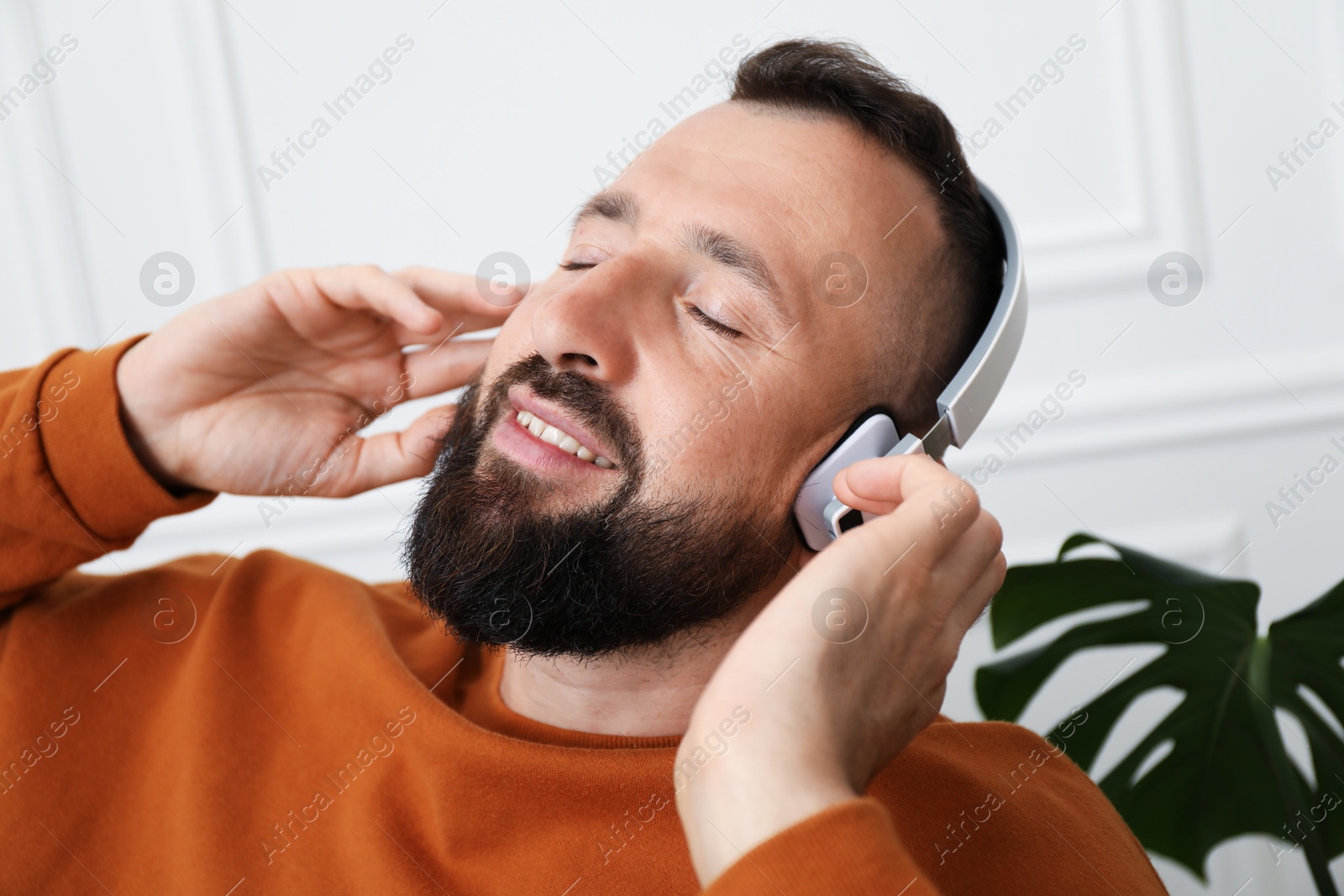 Photo of Harmony. Man listening to music in headphones at home, closeup