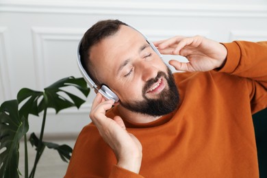 Photo of Harmony. Man listening to music in headphones at home