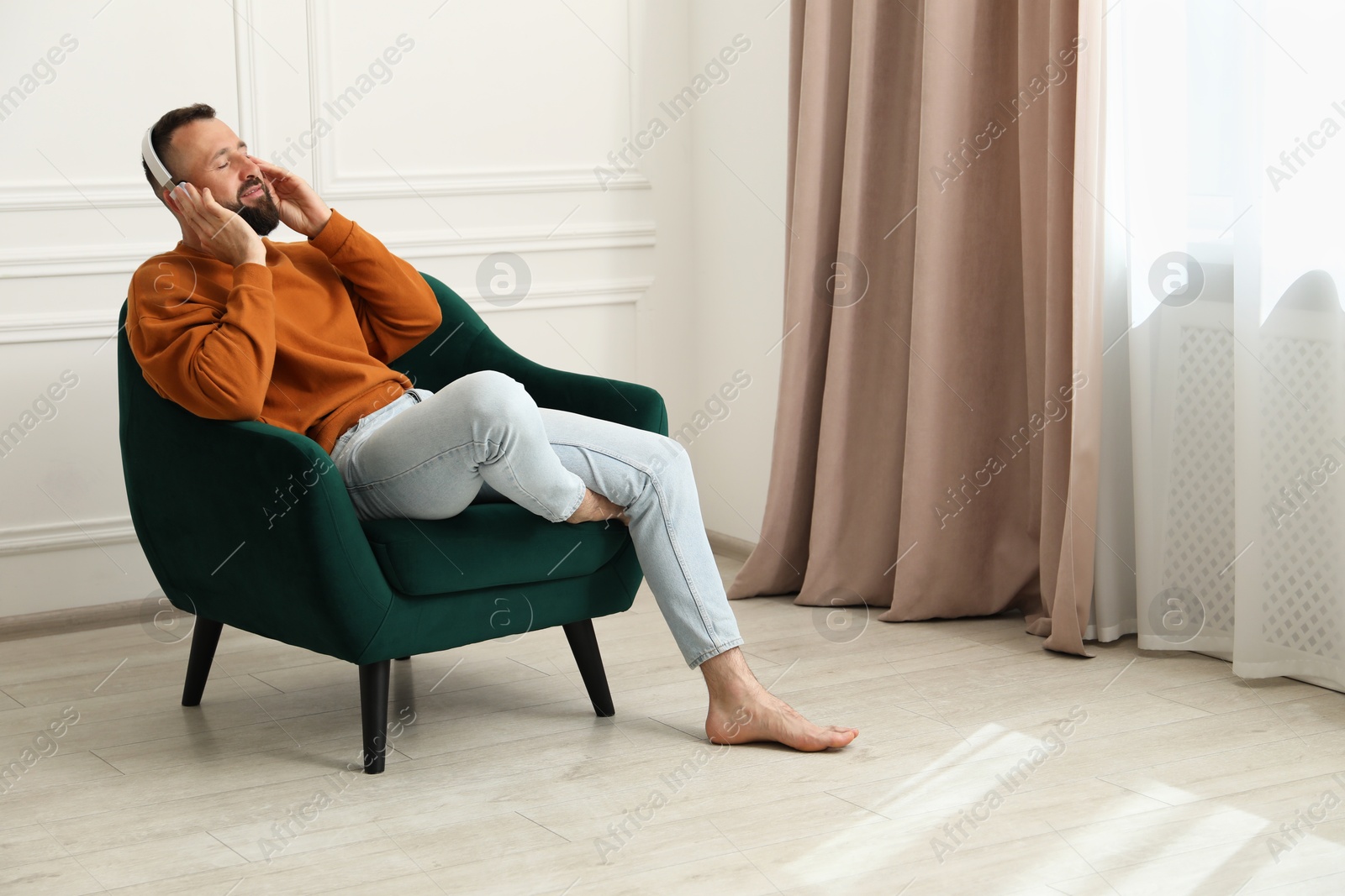 Photo of Harmony. Man listening to music in headphones at home