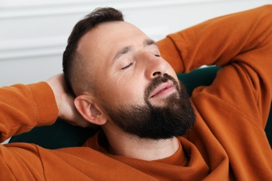 Photo of Harmony. Man relaxing in comfortable armchair at home, closeup
