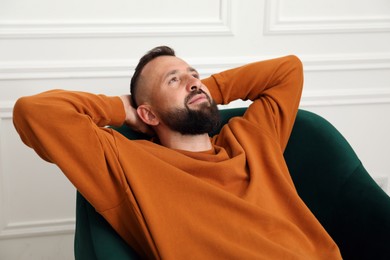 Photo of Harmony. Man relaxing in comfortable armchair at home