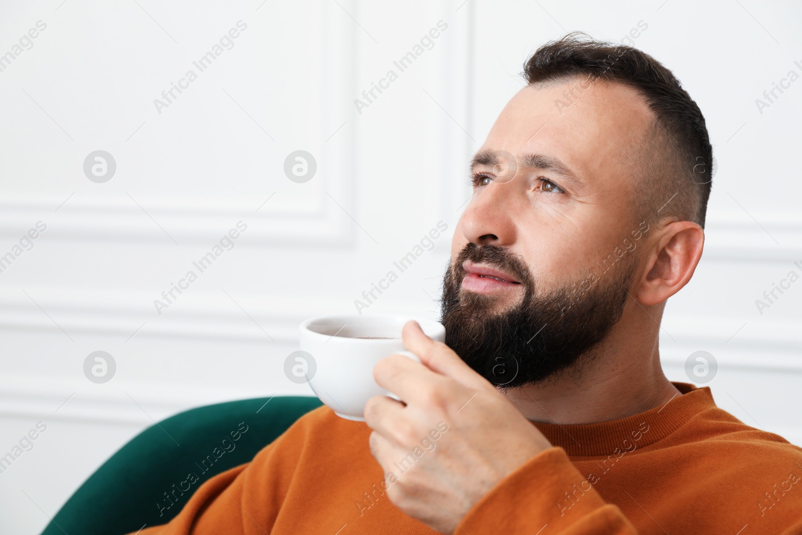 Harmony. Man with cup of drink in armchair at home, closeup Photo of Harmony. Man with cup of drink in armchair at home, closeup