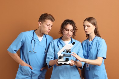 Photo of Group of medical students with microscope on brown background