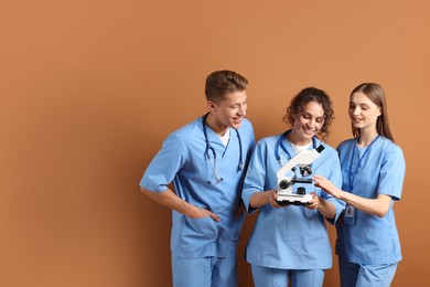 Photo of Group of medical students with microscope on brown background. Space for text