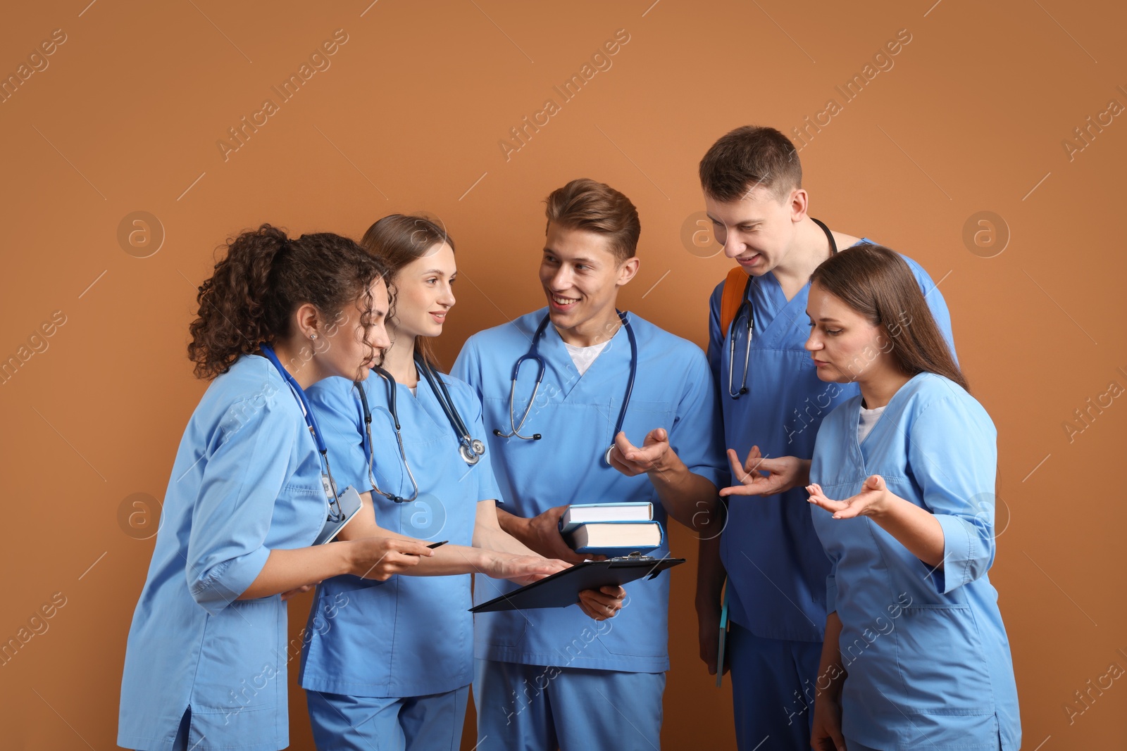 Group of medical students with books on brown background Photo of Group of medical students with books on brown background