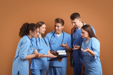 Photo of Group of medical students with books on brown background