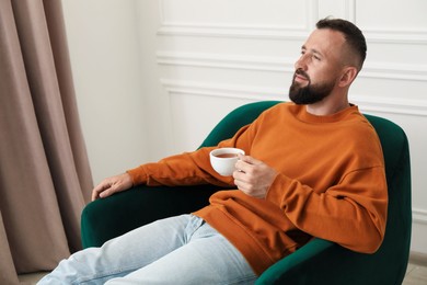 Photo of Harmony. Man with tea in armchair at home
