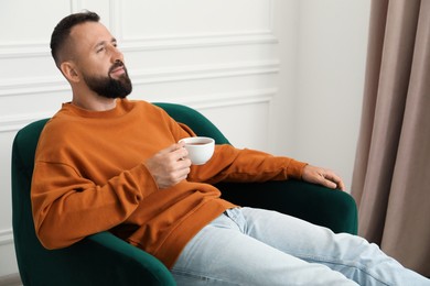 Photo of Harmony. Man with tea in armchair at home
