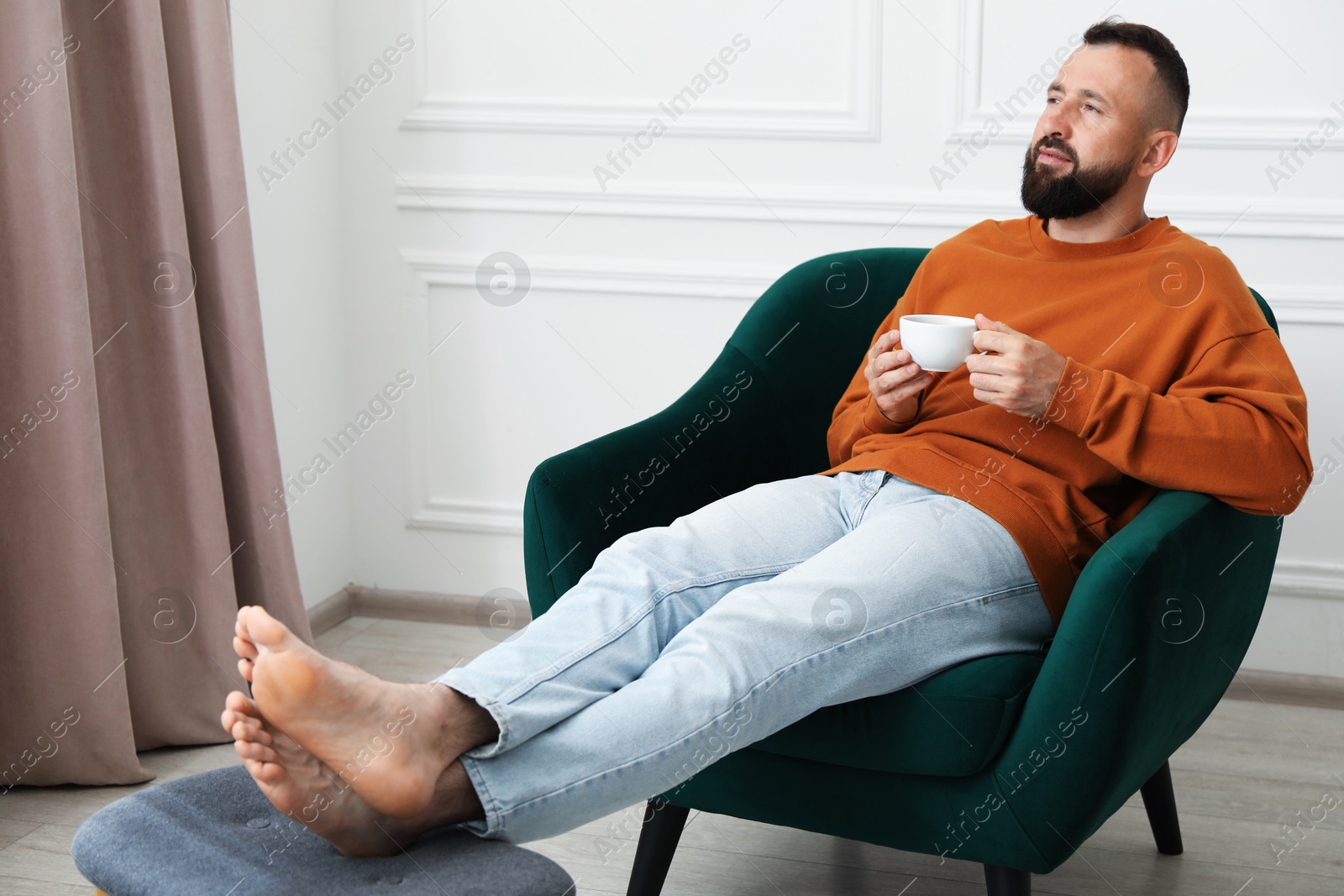 Harmony. Man with cup of drink in armchair at home Photo of Harmony. Man with cup of drink in armchair at home