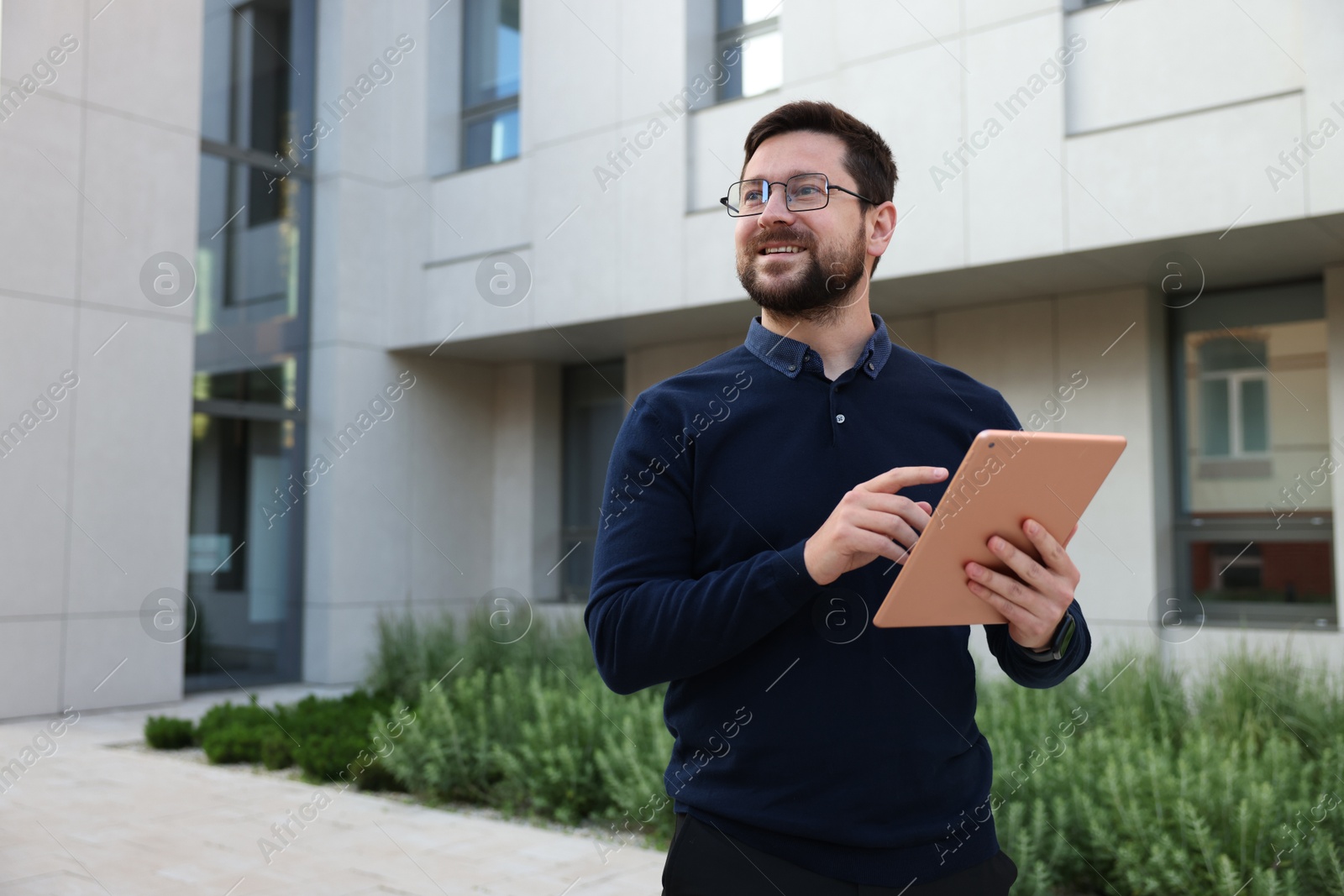 Happy businessman with tablet near office building. Space for text Photo of Happy businessman with tablet near office building. Space for text