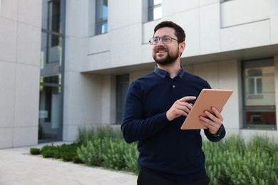 Photo of Happy businessman with tablet near office building. Space for text