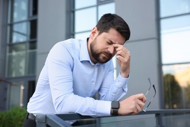 Photo of Tired businessman with glasses outside office building