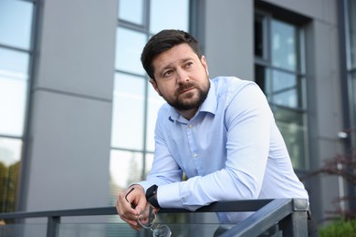 Photo of Tired businessman with glasses outside office building