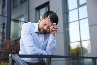 Photo of Tired businessman with glasses outside office building