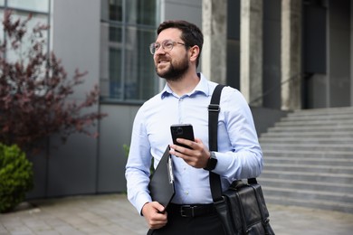 Photo of Successful businessman with smartphone near office building