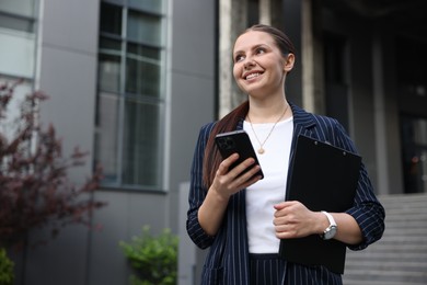 Photo of Happy businesswoman with smartphone near office building. Space for text