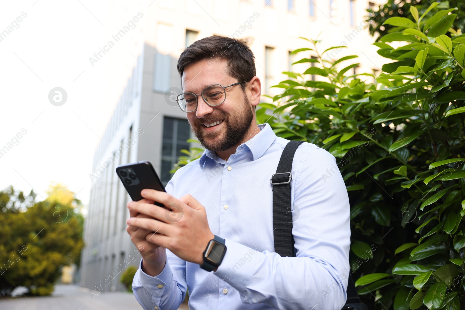 Successful businessman with smartphone near office building Photo of Successful businessman with smartphone near office building