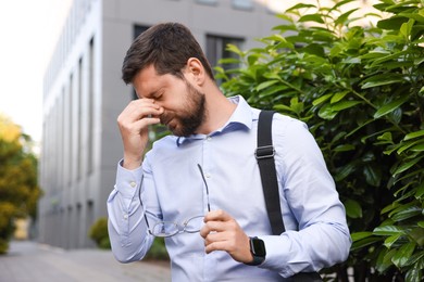 Photo of Tired businessman with glasses outside office building