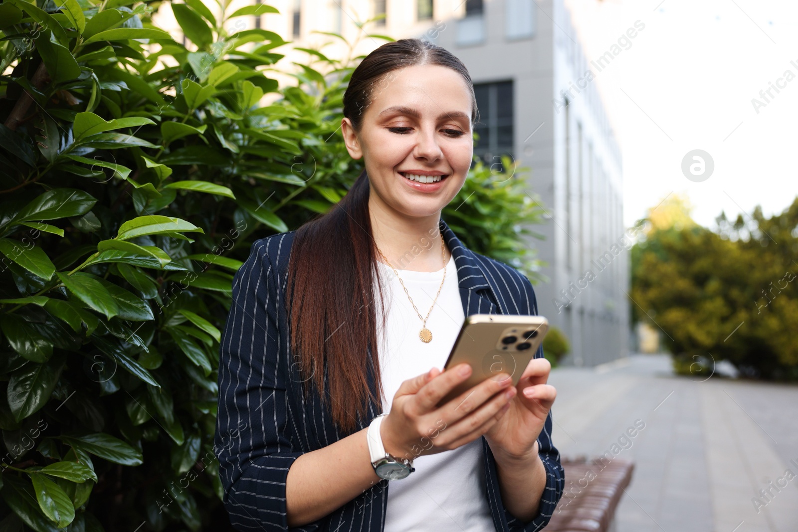 Successful businesswoman with smartphone near office building Photo of Successful businesswoman with smartphone near office building