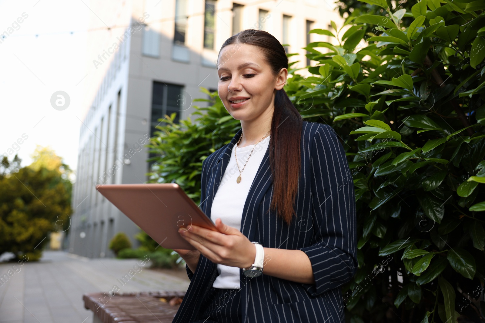 Photo of Successful businesswoman with tablet near office building