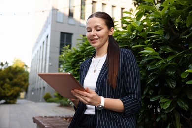 Photo of Successful businesswoman with tablet near office building