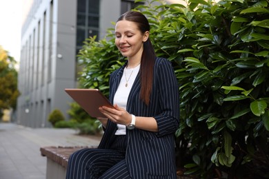 Photo of Successful businesswoman with tablet near office building