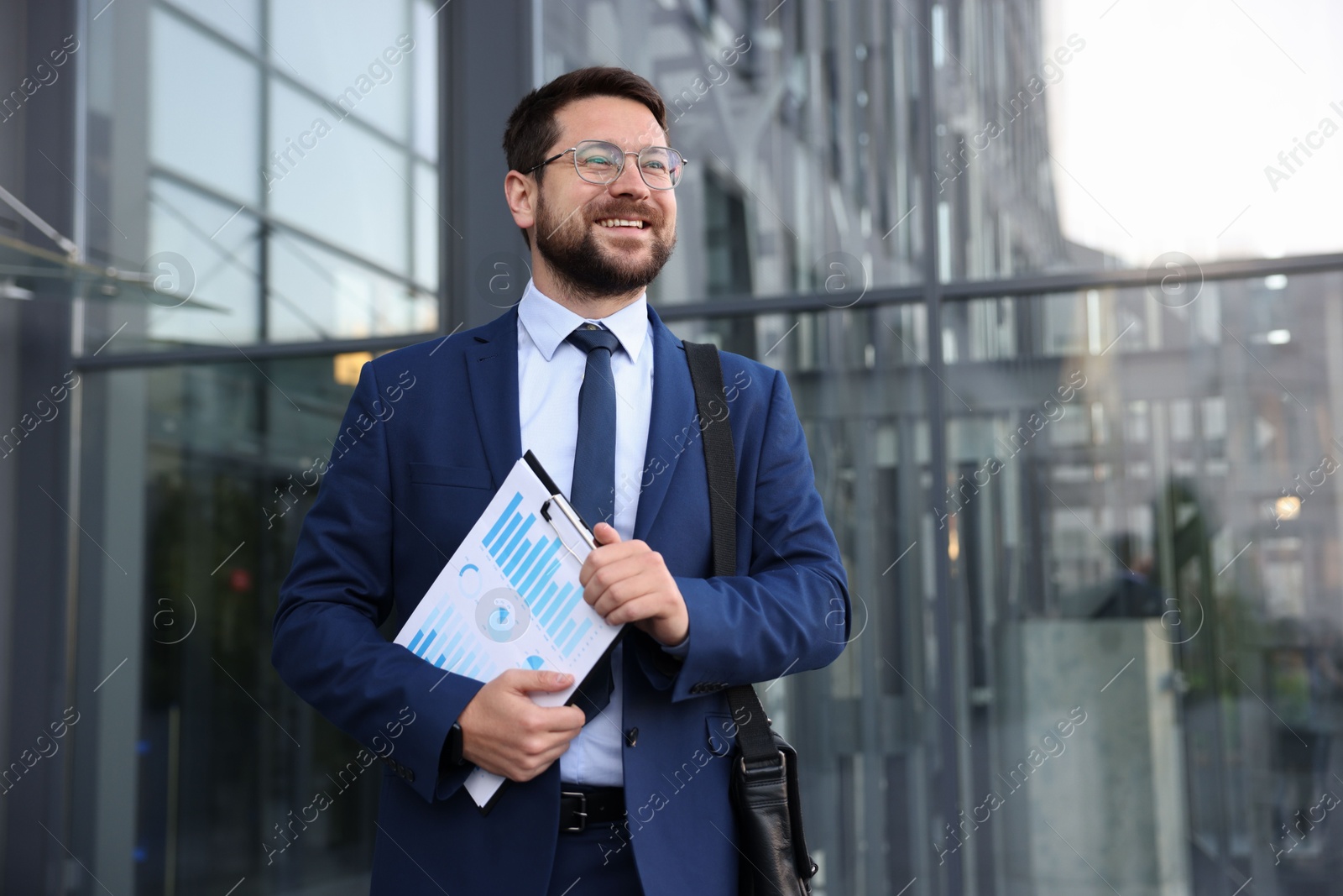Photo of Successful businessman with clipboard near office building