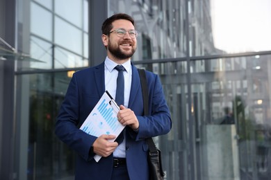 Photo of Successful businessman with clipboard near office building