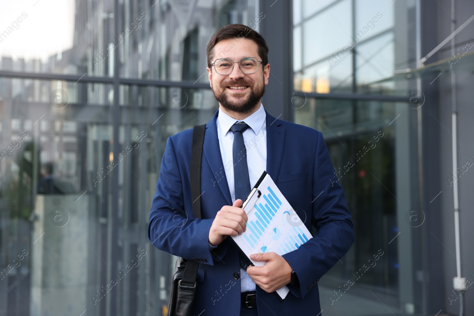 Photo of Successful businessman with clipboard near office building