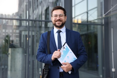 Photo of Successful businessman with clipboard near office building