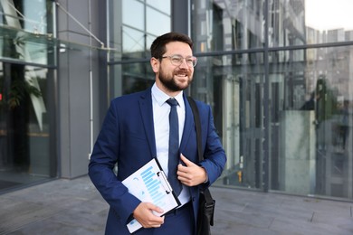 Photo of Successful businessman with clipboard near office building