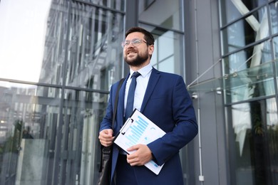 Photo of Successful businessman with clipboard near office building