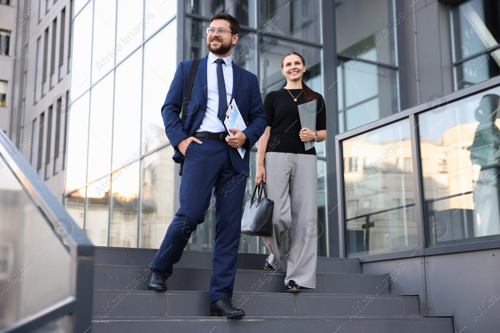 Happy coworkers on stairs near office building Photo of Happy coworkers on stairs near office building