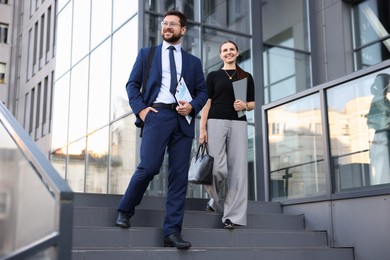 Photo of Happy coworkers on stairs near office building