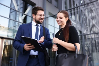 Photo of Happy coworkers discussing something near office building, low angle view