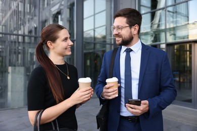 Photo of Happy coworkers with coffee discussing something near office building