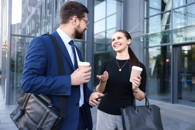 Photo of Happy coworkers with coffee discussing something near office building