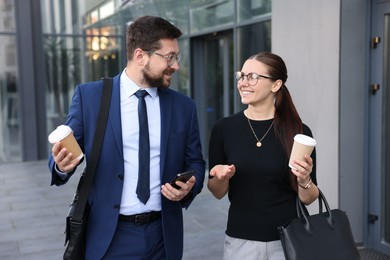 Photo of Happy coworkers with coffee discussing something near office building