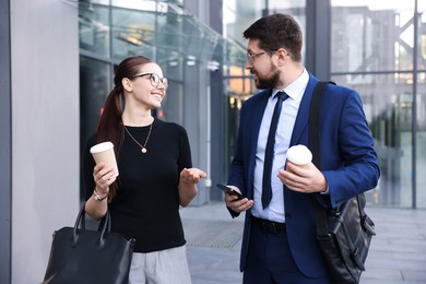 Photo of Happy coworkers with coffee discussing something near office building