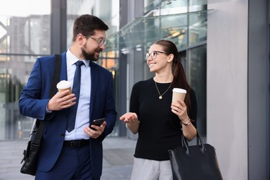 Photo of Happy coworkers with coffee discussing something near office building