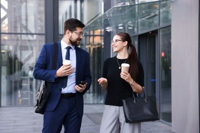 Photo of Happy coworkers with coffee discussing something near office building