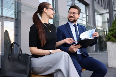 Photo of Happy coworkers discussing something near office building