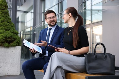 Photo of Happy coworkers discussing something near office building