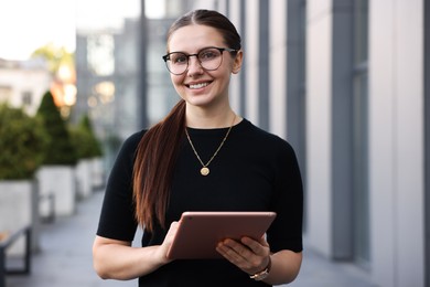 Photo of Successful businesswoman with tablet near office building
