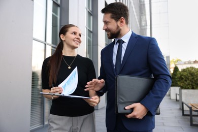 Photo of Happy coworkers discussing something near office building
