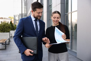 Photo of Happy coworkers discussing something near office building