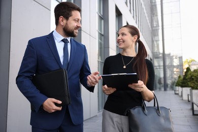 Photo of Happy coworkers discussing something near office building