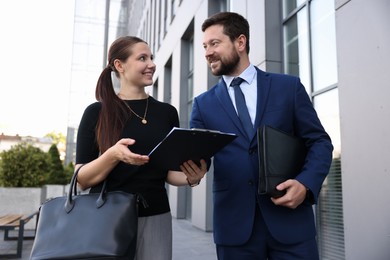 Photo of Happy coworkers discussing something near office building